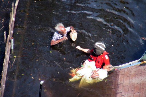 In photo dated September 7 2005 and released on September 9 a Coast Guard rescue swimmer with the pilots from Airstation Atlantic City N.J. prepares an elderly man and woman for transport to safety from the New Orleans flood waters.  (UPI...