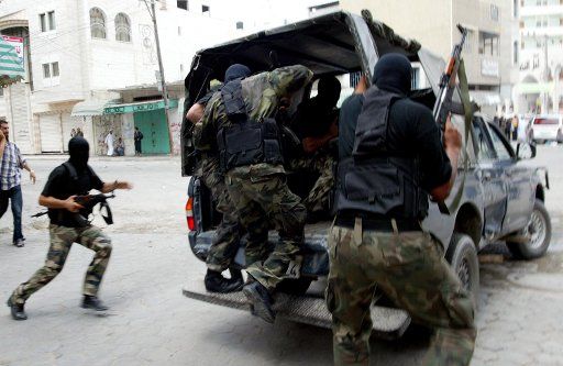 Masked Palestinian police officers exchange gun fire with a group of militants who kidnapped foreigners in the Khan Younis refugee camp southern Gaza Strip Monday Aug. 8 2005. Palestinian gunmen kidnapped the two workers and police freed them minutes...