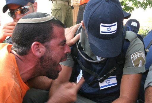 An Israeli settler argues with an Israeli Policeman calling on their consciouses to stop the withdrawal of Israel in Neve Dekalim settlement in the Gush Katif area of Gaza on Aug. 17 2005. Israel started the evacuation by force after the 48 hour...