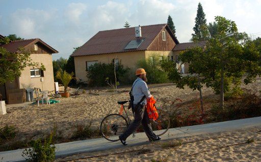 An Israeli settler walks with his bicycle and  gun while waiting to be evacuated from the Jewish settlement Atzmona in the Gaza Strip August 21 2005.  (UPI Photo\/Debbie Hill)