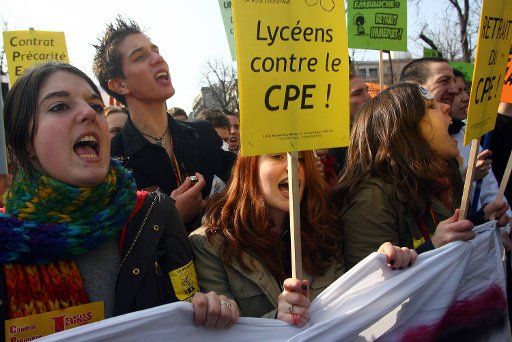 Youths hold banners and shout slogans during a mass demonstration in Paris March 18 2006. Some 400000 protestors took to the street to protest the implementation of the First Employment Contract (CPE) applicable to people under 26 which implies am...