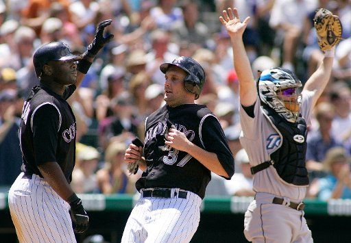 Colorado Rockies Josh Fogg (C) scores after teammate Cho Freeman (L) in the second inning as Toronto Blue Jays catcher Gregg Zaun (R) calls for time at Coors Field in Denver May 21 2006.   (UPI Photo\/Gary C. Caskey)
