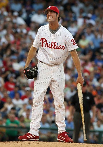 Phillies starting pitcher Coles Hamels has a smile as he picks up the bat after jumping out of the way when New York\