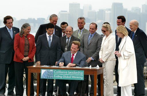 California Governor Arnold Schwarzenegger (sitting) signs the California Global Warming Solutions Act of 2006 to reduce California\