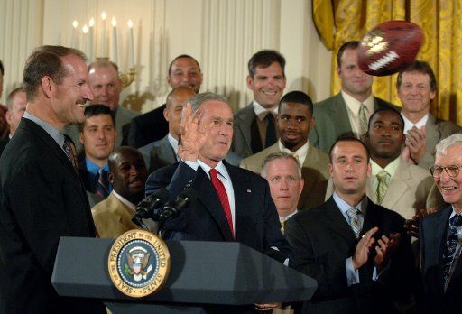 U.S. President George W. Bush throws a pass to Pittsburgh Steelers Hines Ward (not shown) during a celebration of the Steelers Super Bowl XL championship in the East Room of the White House on June 2 2006.  At left is Steelers Head Coach Bill Cowher...