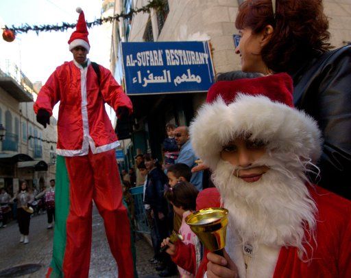 A Palestinian boy dressed like Santa Claus rings a bell during a parade in the biblical city of Bethlehem where tradition says Jesus was born in the West Bank on December 24 2006. (UPI Photo\/Debbie Hilll)