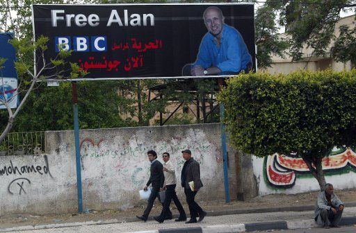 Palestinian men walk next to a poster showing kidnapped BBC Gaza correspondent Alan Johnston in Gaza City on April 17 2007. A previously unknown Palestinian group kidnapped  the British journalist  over a month ago by gunmen in Gaza City. (UPI...