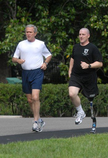 U.S. President George W. Bush runs alongside Army Specialist Max Ramsey who lost his leg in Iraq in March 2006 on the South Lawn of The White House in Washington on July 25 2007. (UPI Photo\/Kevin Dietsch)