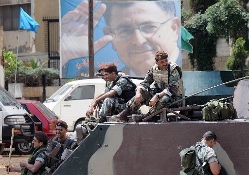 Soldiers take a rest below a portrait of Prime Minister Fuad Saniora as clashes between pro government and the Hezbollah led opposition continue throughout Lebanon for a second day leaving many parts of Beirut and other towns and villages deserted ...