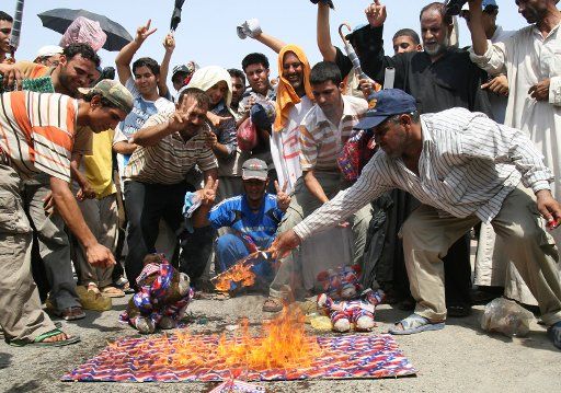 Supporters of Iraqi cleric Muqtada al-Sadr burn items depicting the United States flag as they demonstrate against the U.S.-Iraqi security agreement in the Shiite enclave of Sadr City in Baghdad Iraq on Friday September 5 2008. (UPI Photo\/Ali ...