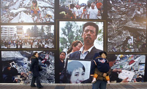 Chinese walk past a massive sidewalk photography exhibit of tragic images taken after the killer 2008 earthquake hit Sichuan in Beijing January 14 2009. The government\