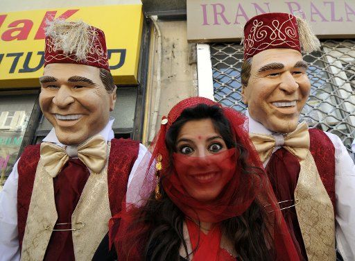 An Israeli woman wears a costume while posing in front of large U.S. President George W. Bush dolls at a Purim celebration in central Jerusalem March 23 2008. Purim commemorates the miraculous salvation of the Jews from Haman the anti-Semitic ...