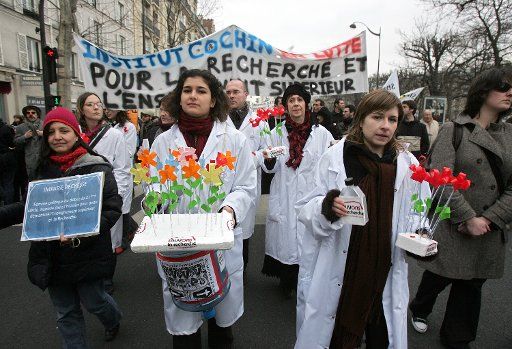 French university students and researchers carry flowers as they reenact the slow death of university studies and research during a protest in Paris February 26 2009 in Paris. Thousands took to the streets of the capital to demonstrate against ...