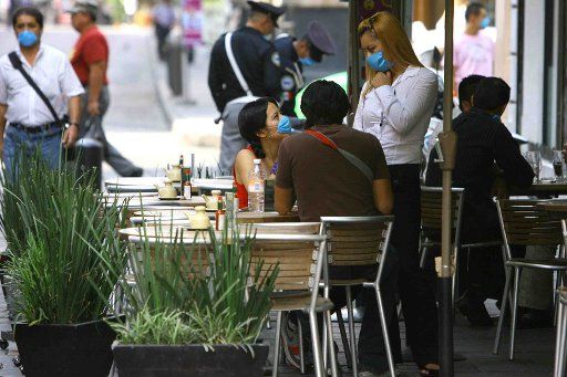 Mexico City residents wear protective masks as they chat at a sidewalk cafe in downtown area area on April 27 2009. The death toll from the swine flu epidemic in Mexico doubled on Monday and the World Health Organization raised the alert level. (...