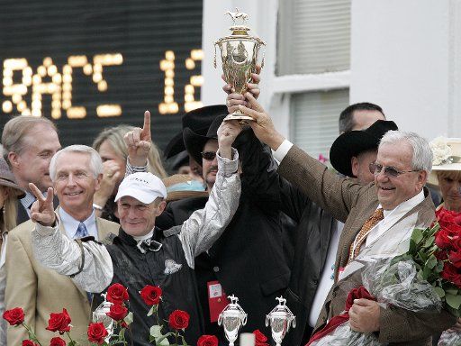 Jockey Calvin Borel left and owner Leonard Blach right hold up the winner\