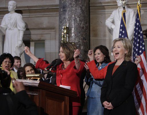 House Speaker Nancy Pelosi (C) (D-CA) greets the audience as U.S. Secretary of State Hillary Clinton (R) reacts during a Women\