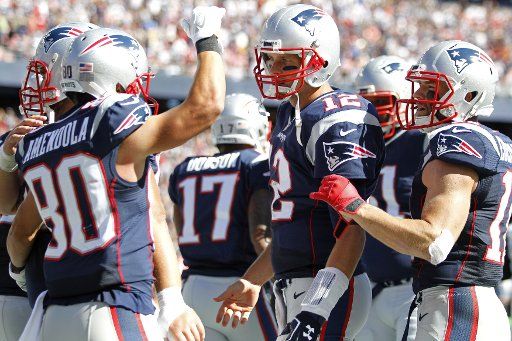 New England Patriots quarterback Tom Brady (12) is congratulated by wide receiver Danny Amendola (80) after the two connected for Brady\