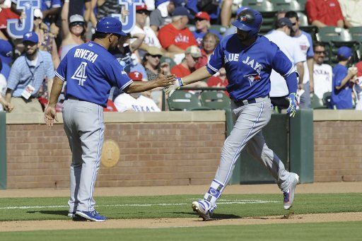 Toronto Blue Jays Chris Colabello is congratulated by third base coach Luis Rivera after hitting a first inning home run off of Texas Rangers pitcher Derek Holland in the first inning of game 4 of the ALDS at Rangers Ballpark in Arlington, Texas on ...