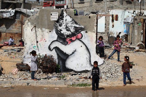 Palestinian child stands next to a mural of a kitten, said to have been painted by British street artist Banksy, on the remains of a house that was destroyed during the 50-day war between Israel and Hamas militants in the summer of 2014, in the Gaza ...