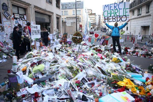 People gather at a memorial site, near the offices of Charlie Hebdo, to lay flowers, light candles and mourn for the victims of the terror attack on the weekly newspaper in Paris, on January 14, 2015. The latest edition of Charlie Hebdo which came ...