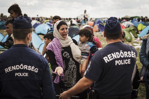 Syrian woman cries as Hungarian police block refugees at the Reszke crossing in Hungary on the border with Serbia on September 8, 2015. Syrian and other refugees are sleeping for days in the fields waiting their chance to get a bus that will take ...