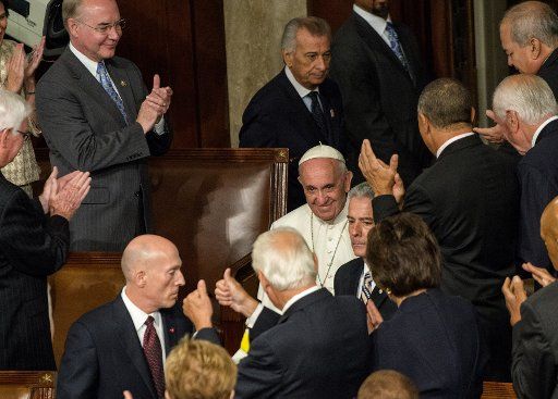 Pope Francis smiles as he is applauded by both sides of the aisle as he enters to become the first Pope to address a joint meeting of Congress at the U.S. Capitol in Washington, DC on September 24, 2015. Republicans are at left and Democrats are at ...
