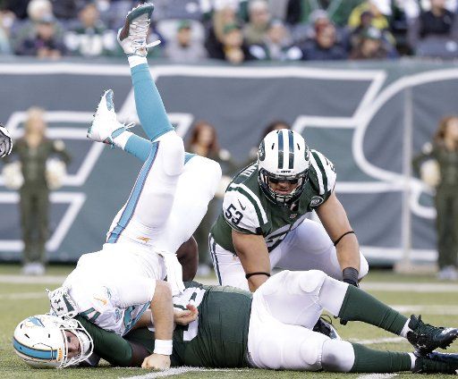 New York Jets Mike Catapano watches Muhammad Wilkerson tackle Miami Dolphins Ryan Tannehill who lands on his head after throwing a pass at MetLife Stadium in East Rutherford, New Jersey on November 29, 2015. The Jets defeated the Dolphins 38-20. ...