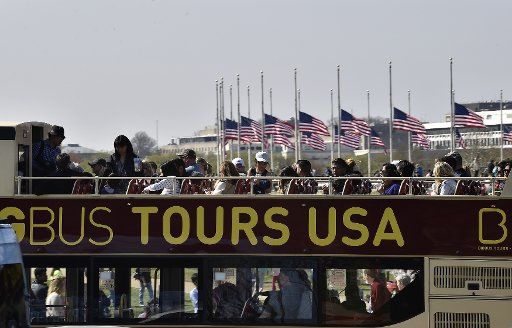 A tour bus passes flags at half-staff to honor victims of the Brussels, Belgium, terrorist attacks during the National Cherry Blossom Festival in Washington, D.C., March 26, 2016. Photo by David Tulis\/