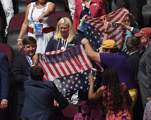 Attendees use American flags to block a Code Pink demonstrator from the media and delegates on day two of the Republican National Convention at Quicken Loans Arena in Cleveland, Ohio on July 19, 2016. Donald Trump will formally accept the ...