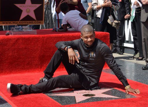 Singer, songwriter and actor Usher lies next to his star during an unveiling ceremony honoring him with the 2,588th star on the Hollywood Walk of Fame in Los Angeles on September 7, 2016. Photo by Jim Ruymen\/