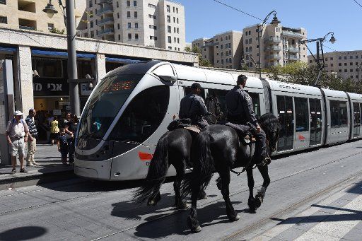 Israeli border police ride horses past the light rail train in Jerusalem, Israel, before Rosh HaShanah, the Jewish New Year, that starts at sunset, October 2, 2016. Photo by Debbie Hill\/