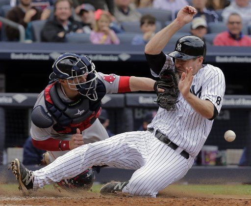 New York Yankees runner Chase Headley (R) is safe at the plate as the ball hits him and Boston Red Sox catcher Christian Vazquez cannot make the catch in the eighth inning of their American League MLB game at Yankee Stadium in New York City, May 7, ...