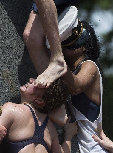 A U.S. Naval Academy Plebes has fed face stepped on as they work together during the annual Herndon Monument Climb, attempting to scale the lard covered monument to replace the plebeian hat at the top with an officer\