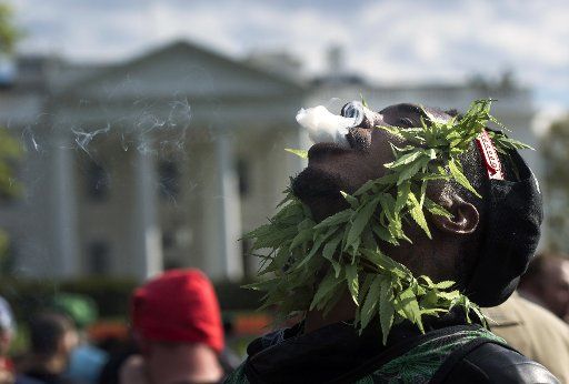 A pro-legalization marijuana supporter smokes in front of the White House with other supporters at 4:20 p.m. during a protest to urge President Barack Obama to stop marijuana arrest, pardon offenders and give greater access to medical marijuana and ...