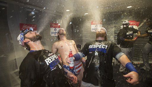Los Angeles Dodgers Josh Reddick (C) and teammates celebrate their win in the locker room after game 5 of the National League Division Series at Nationals Park on October 13, 2016. Los Angeles will face the Chicago Cubs in the NLCS after defeating ...