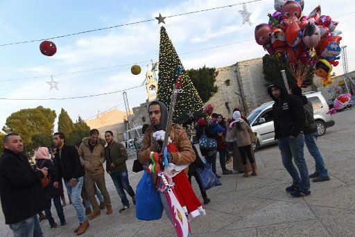 A Palestinian sells Santa hats outside the Church of Nativity, where tradition believes Jesus Christ was born, in the biblical town of Bethlehem, West Bank, December 22, 2016. Photo by Debbie Hill\/