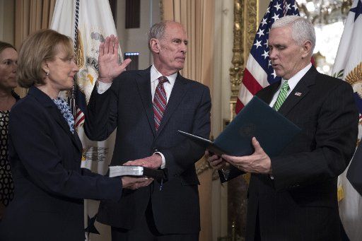 U.S. Vice President Mike Pence (R) administers the oath of office to Director of National Intelligence Dan Coats (C), with his wife Marsha Coats (L), during a swearing in ceremony in the US Capitol in Washington, DC on March 16, 201. Pool Photo by ...