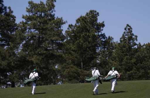 Three caddies walk up the first hole fairway at a practice round at the 2017 Masters Tournament at Augusta National Golf Club in Augusta, Georgia on April 2, 2017. Photo by John Angelillo\/