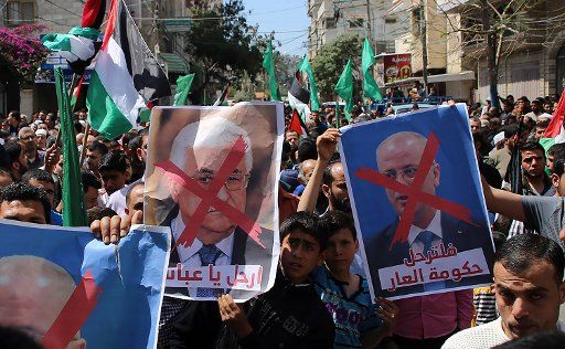 Supporters of the Palestinian Hamas movement hold crossed-out portraits of Palestinian leader Mahmoud Abbas (L) and Prime Minister Rami Hamdallah during a protest against the Israeli blockade of the Gaza Strip in Khan Younis in the southern Gaza ...