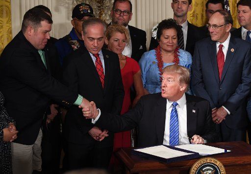 U.S. President Donald Trump shakes hands at the signing of the "VA Accountability and Whistleblower Protection Act" during an event in the East Room of the White House in Washington, DC on June 23, 2017. The act is designed to make it easier to ...