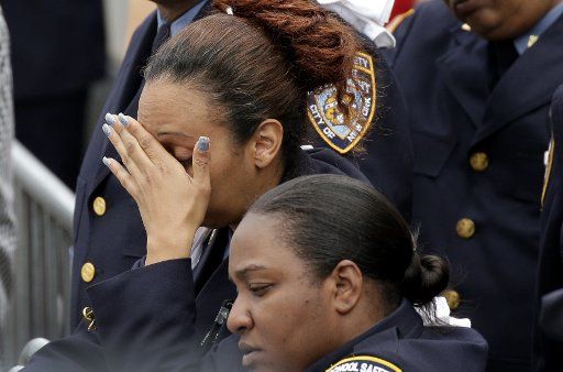 A Police officer reacts outside the funeral of NYPD Police officer Miosotis Familia at World Changers Church in Fordham Heights in New York on July 11, 2017 in New York City. NYPD officer Miosotis Familia was shot and killed while sitting inside her ...
