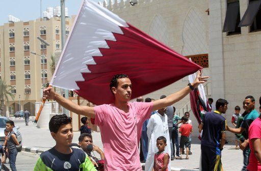 A Palestinian man holds a Qatari flag during a rally in support of Qatar, inside Qatari-funded construction project \