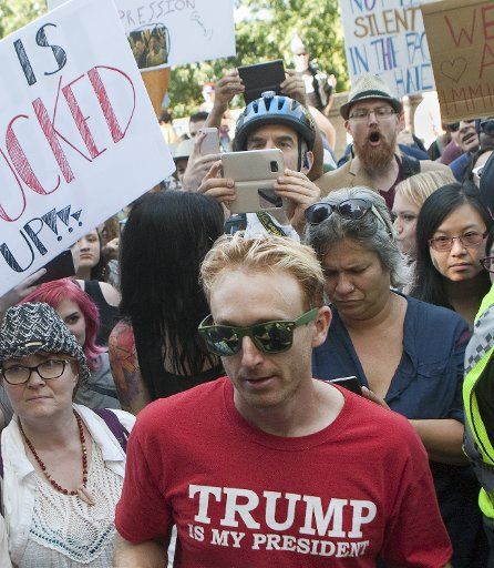 Vancouver Police protect a man who identifies as Brendan (red t-shirt) from the far-right rally as he argues his point of view while surrounded by dozens of the thousands counter protesting the small far-right rally at Vancouver City Hall in ...