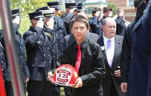 The grandson of the late St. Louis fire captain John Kemper, Ethan Barczewski (11), carries his grandfathers helmet as he walks through a sea of blue following funeral services at Harris Stowe State College in St. Louis on July 21, 2017. Kemper died ...