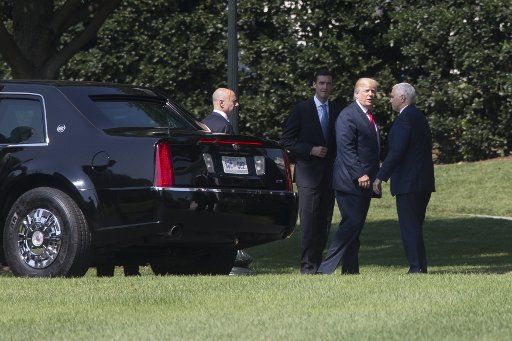 President Donald J. Trump (C) stands near the armored limousine known as \