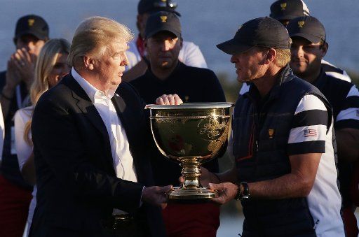 United States President Donald Trump hands Captain of the United States Team Steve Stricker the trophy after defeating the International team 19 to 11 total points at the Presidents Cup on October 1, 2017 at Liberty National Golf Club in Jersey City,...