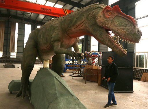 A Chinese technician remotely controls a robotic dinosaur at the Gengulongteng Science and Technology Company\