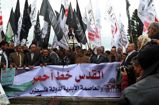 Palestinian men hold slogans during a protest in Gaza City on December 6, 2017. The slogan in Arabic reads: "Jerusalem is a red line, Jerusalem is the eternal capital of Palestine" President Donald Trump is set to recognize Jerusalem as Israel\