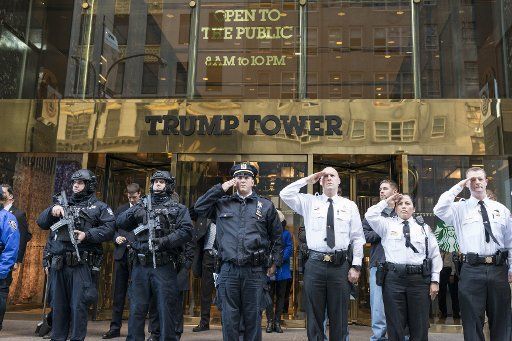Security personnel at Trump Tower stand and salute awaiting the funeral procession to nearby St. Patrick\