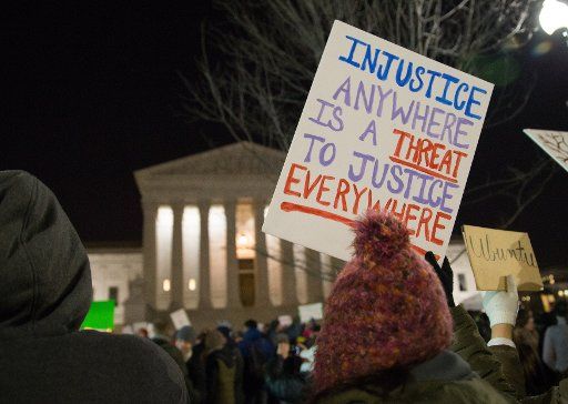 A protester holds up a sign in front of the U.S. Supreme Court to call on U.S. President Trump to reverse his administration\